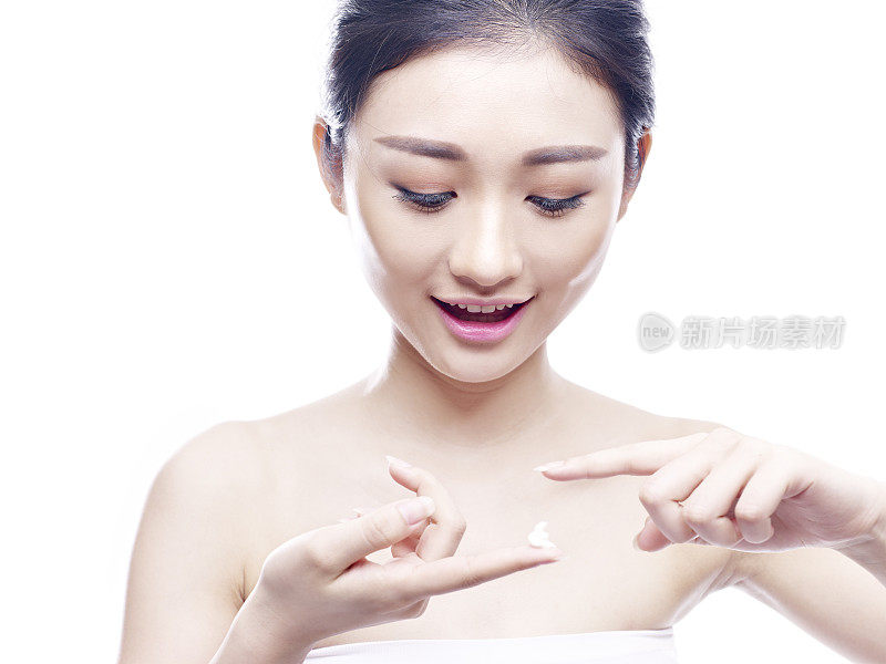 年轻的亚洲女性在脸上涂乳液