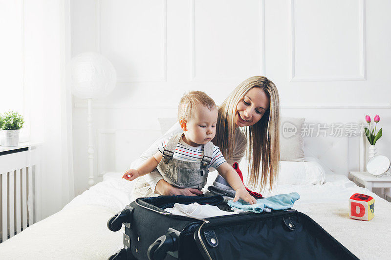和孩子一起旅行。快乐的母亲和她的孩子打包衣服度假