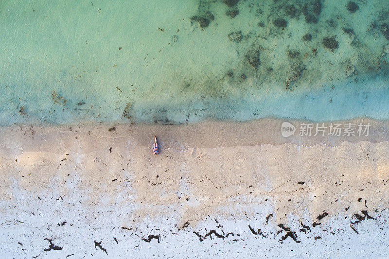 无人机拍摄的美丽的年轻女子穿着蓝色比基尼在泰国苏梅岛的一个伟大的海滩上