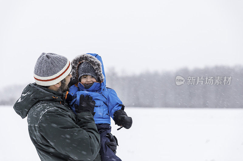 父亲和儿子在户外玩冬天森林暴风雪