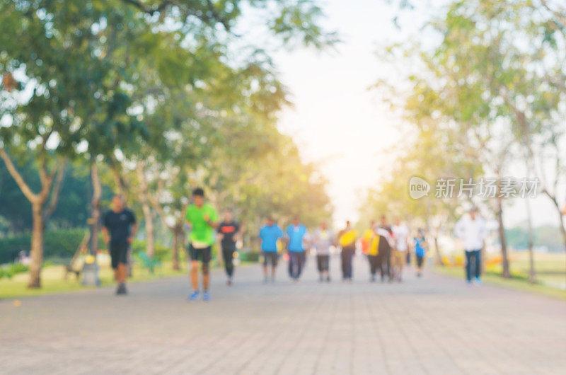 一群人每天早晨在阳光明媚的公园里跑步或慢跑，以保持身体健康。