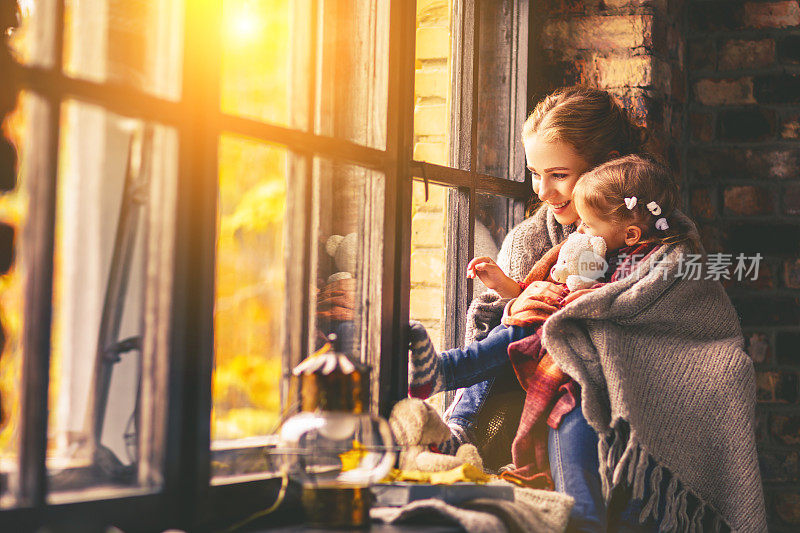 幸福的家庭妈妈和宝宝在秋天的窗口