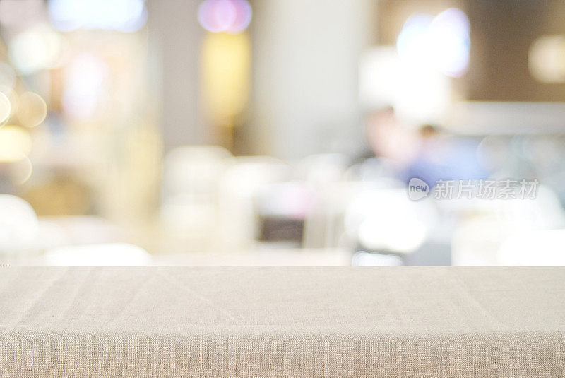 空桌面与亚麻桌布在模糊的咖啡馆与散景背景，复制空间的食物和产品显示蒙太奇背景