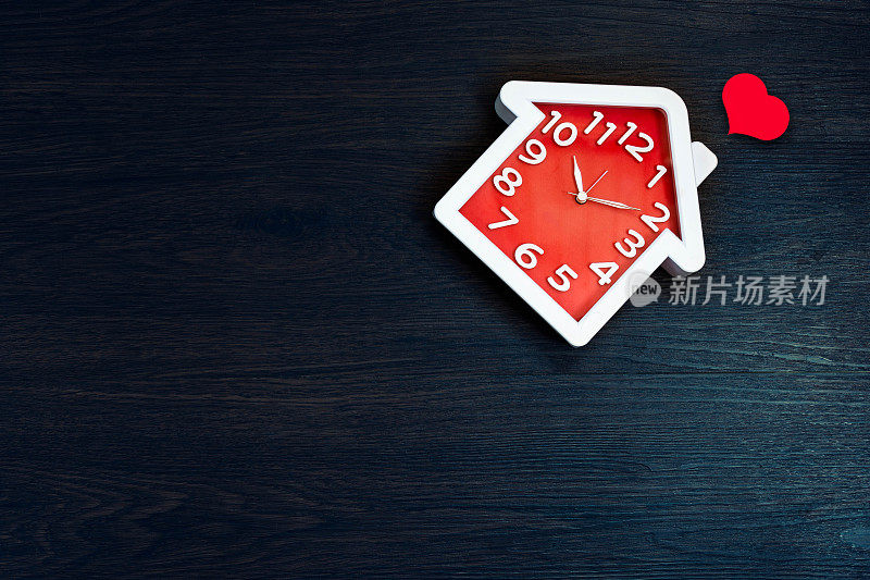 家形状时钟在地板上的背景与红色的心图标。幸福生活与家庭理念。内部和对象主题。时间以日常生活为主题。