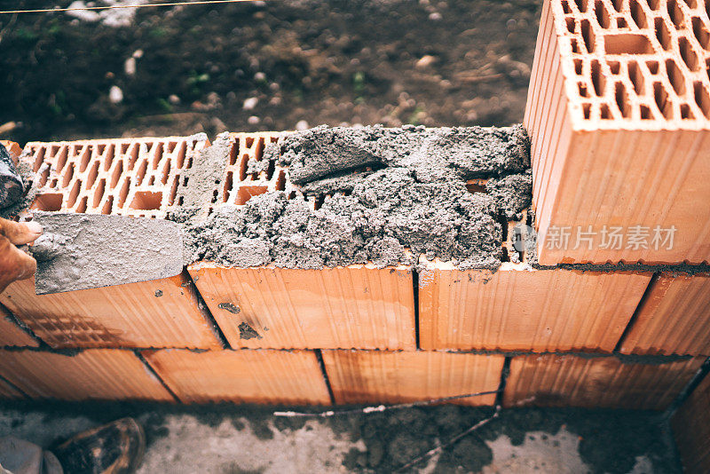工业工人使用泥铲和工具用砖块、灰浆和混凝土建造外墙