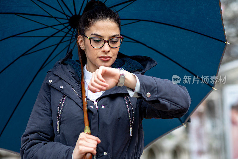 美丽的年轻女子站在汽车站等车。