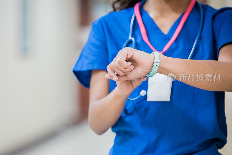 医院里面目全非的女护士在值班时检查健身追踪器或智能手表