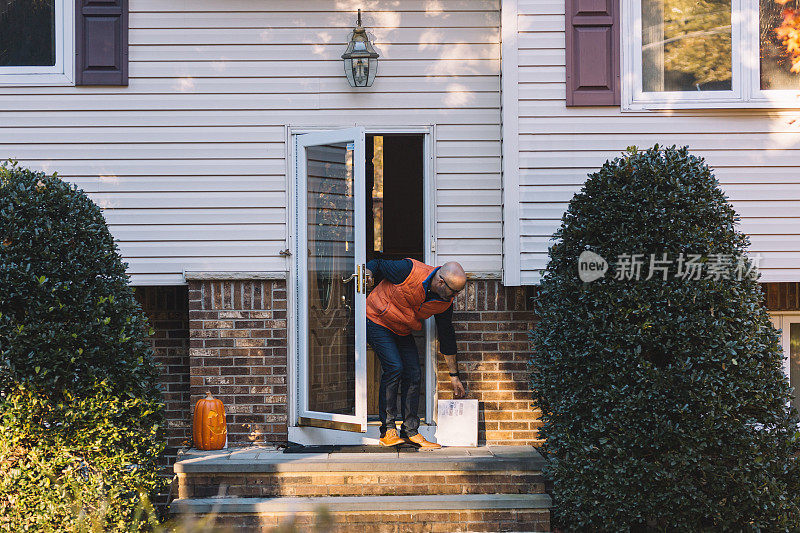 一名男子在家门口拾取包裹