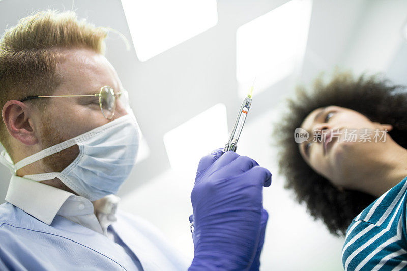 牙医用注射器和口镜给病人进行局部牙齿麻醉