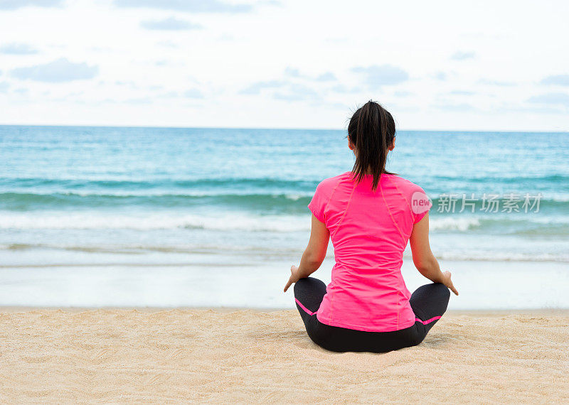 年轻女子在海滩上做瑜伽冥想