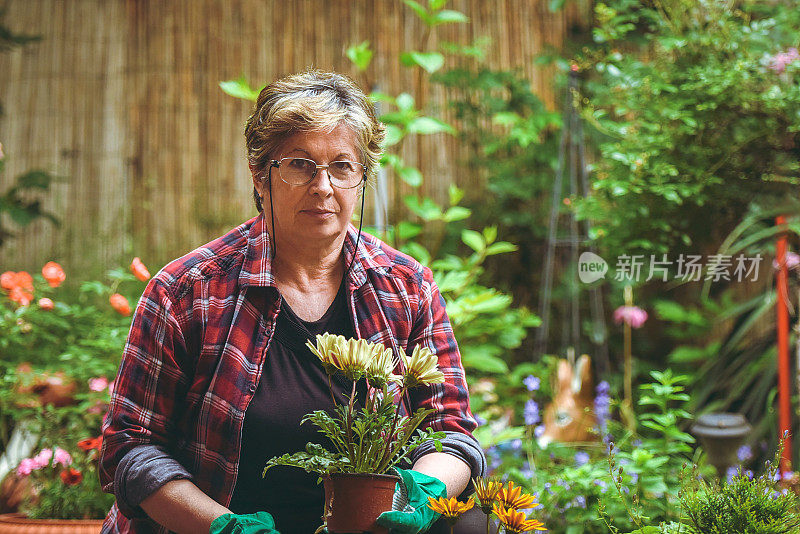 年长的女人在花园里带着花