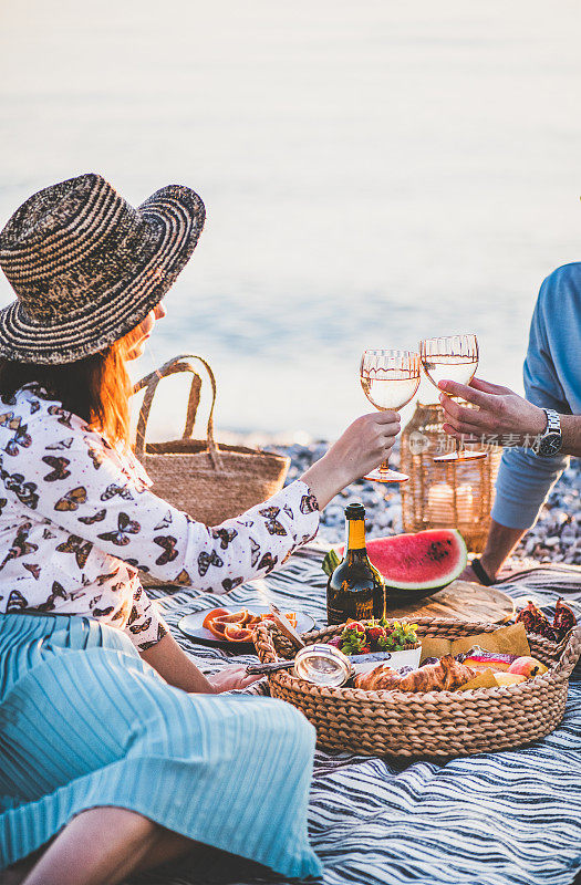 一对夫妇在海边野餐与起泡酒和水果