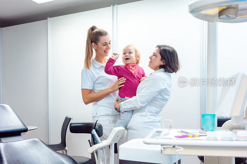 牙医和她的助手带着孩子在办公室里
