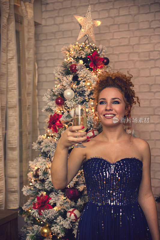 庆祝的时候了。漂亮的女孩拿着香槟站在圣诞树前