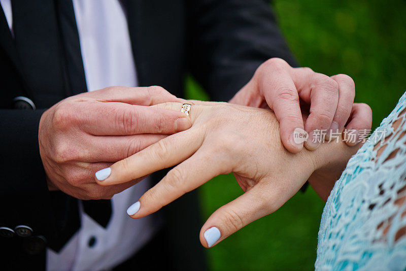 新郎和新娘手拿结婚戒指，一个男人向一个女人求婚，浪漫的婚纱照
