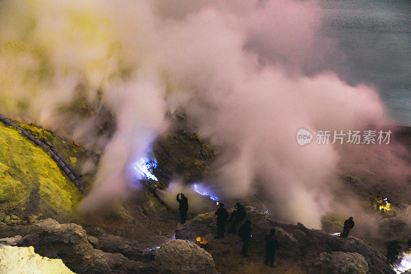 印度尼西亚东爪哇，伊真火山的壮观日出，蓝色的火焰和明亮的黄色硫磺蒸汽在绿松石湖之上