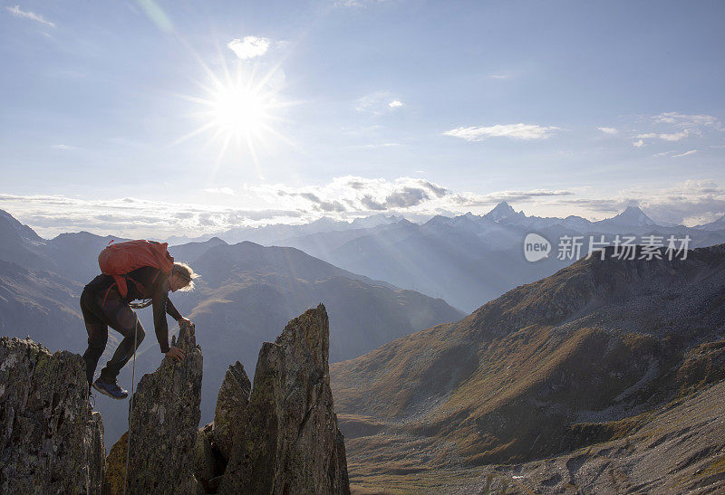 日落时，登山者爬上岩石的顶峰