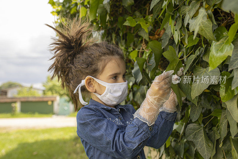 小女孩戴着防护面具在花园里