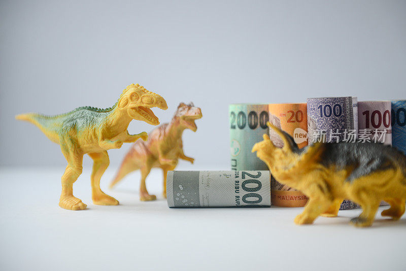 林吉特和印尼盾卷钞票，恐龙模型和房子模型的白色背景