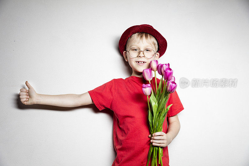 男孩拿着粉红色的郁金香花开心地笑着做ok手势，用手指竖起大拇指，很棒的手势