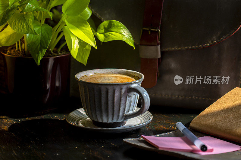 休息时间:记事本，公文包和咖啡放在木桌上