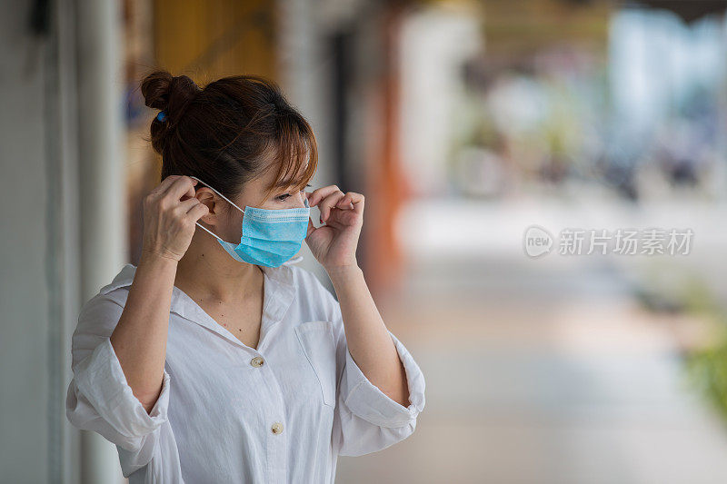 在新冠肺炎封锁期间，戴口罩以预防流感的亚洲妇女外出购物。