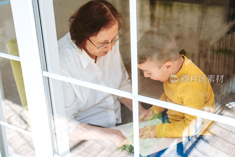 祖母在为因冠状病毒-冠状病毒19隔离而不能出门的小孙子读书