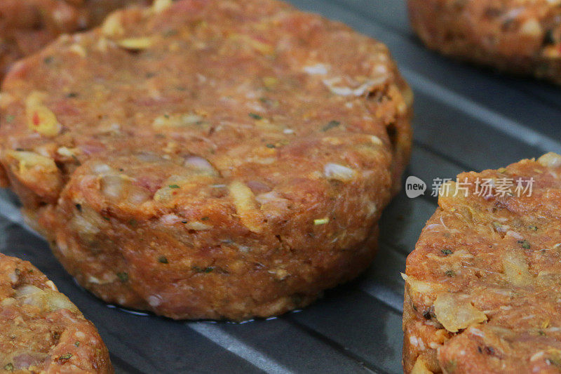 特写的自制牛肉汉堡肉饼，烤盘在厨房的工作台上准备在烤箱中烹饪