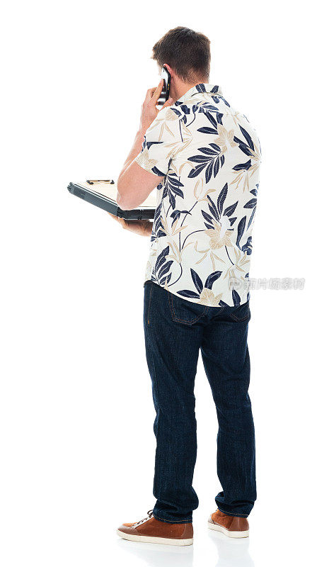 白人男性穿着牛仔裤站在白色背景前，拿着待办事项清单，使用手机