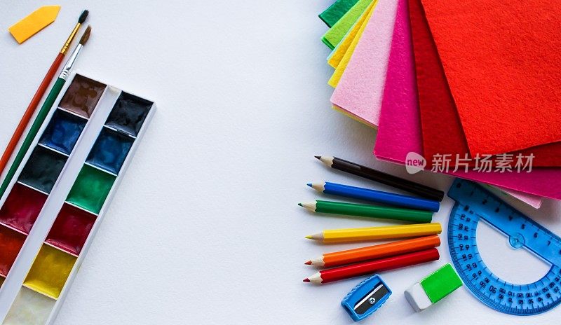 平面文具学校和创意，绘画和工艺品(水彩画颜料，彩色铅笔，彩色毛毡)的背景白色纹理水彩纸和文字空间