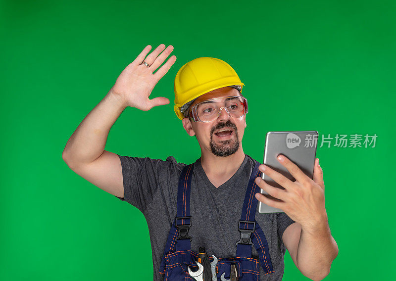 建筑工人在绿色背景下使用数字平板电脑进行视频通话