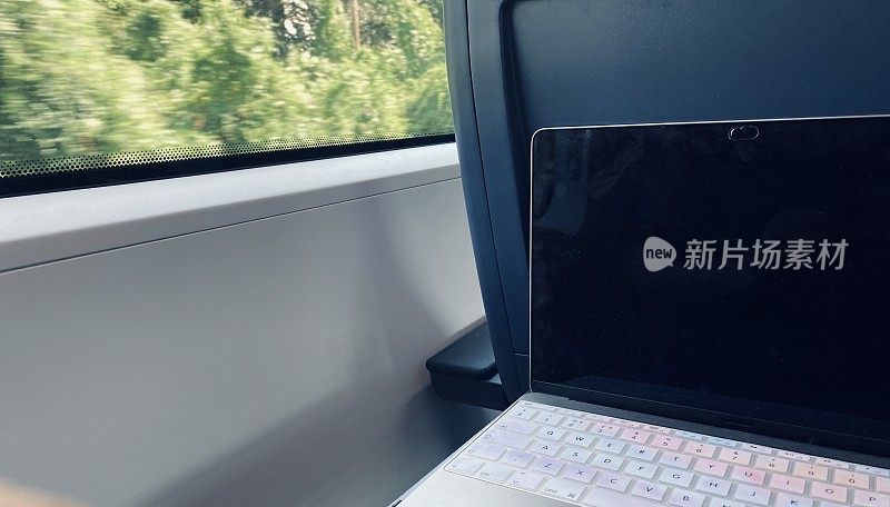 在火车上用笔记本电脑工作，外面是风景