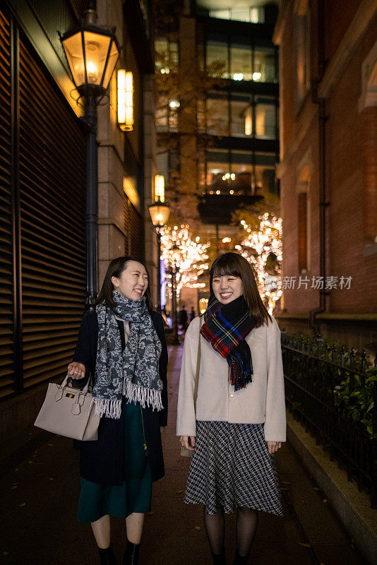 年轻女性下班后走在城市里享受购物和圣诞彩灯