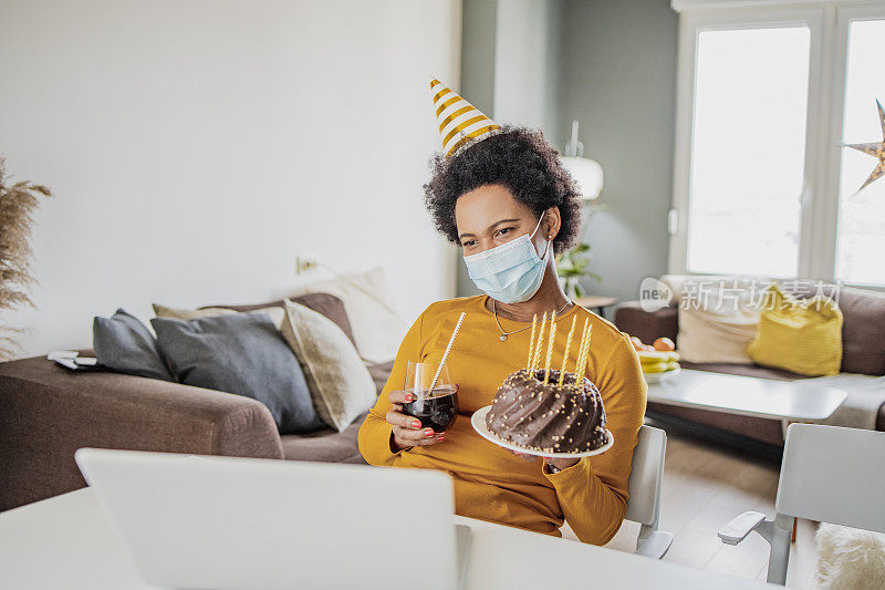 一位戴着面具的非洲妇女在视频通话中庆祝生日