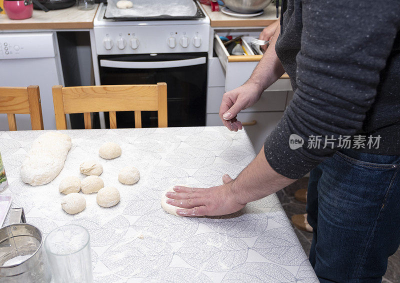 一个男人用面团做馅饼和小面包。男手特写。