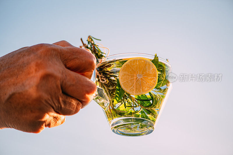 拿着迷迭香茶和柠檬的女人