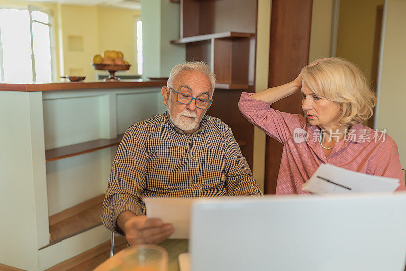 一对老夫妇正在用笔记本电脑支付网上账单。