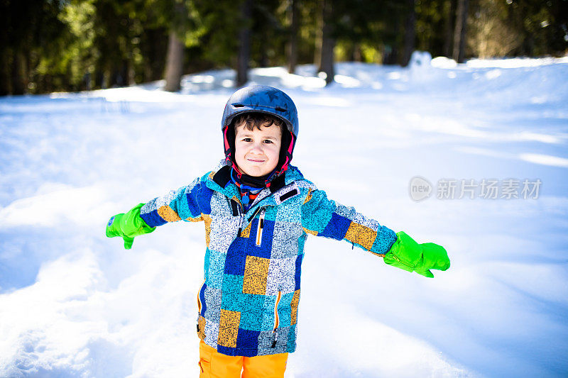 一个男孩站在雪地里准备做一个雪天使