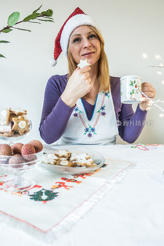 女人喜欢圣诞饼干和茶在圣诞帽