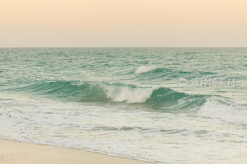 在佛罗里达棕榈滩的海岸线上的蓝绿色海浪上的柔和的日落