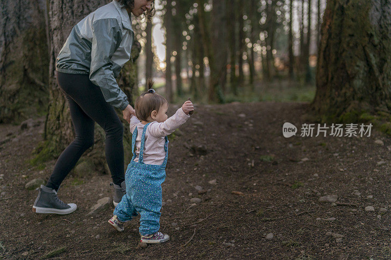 在日落时分，年轻的母亲慈爱地和她的孩子在森林里散步