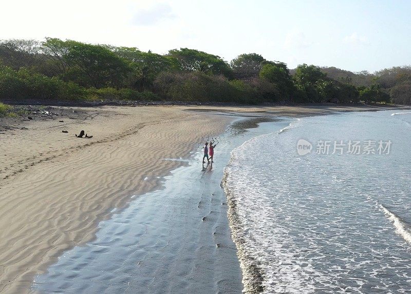 鸟瞰图的成熟夫妇走下海滩在日出