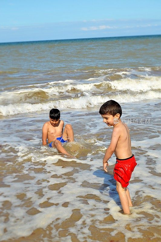 一个夏日，两个男孩在海滩上观察海浪