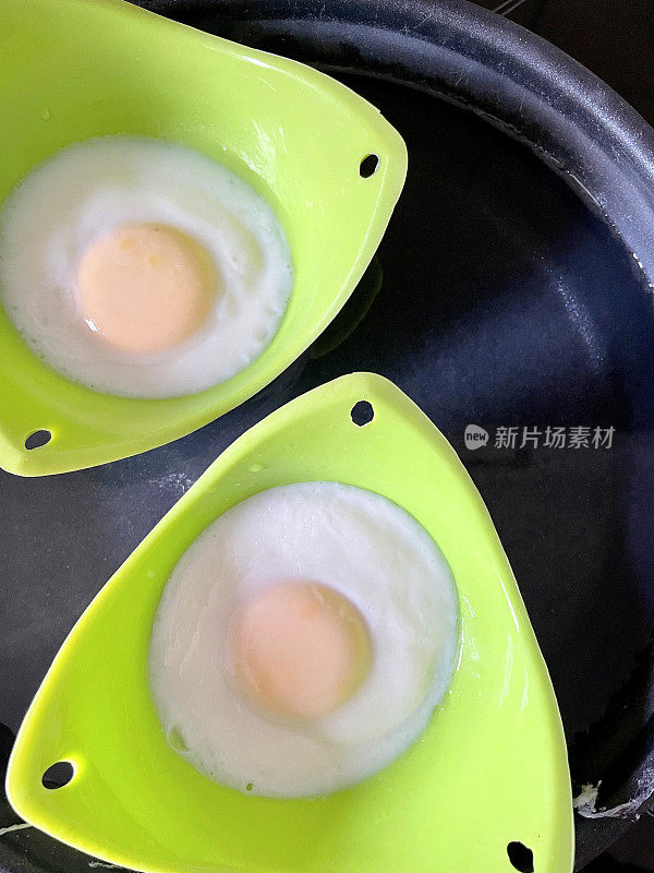 绿色的有机硅鸡蛋，在热水煎锅里盛着煮熟的鸡蛋，高视化