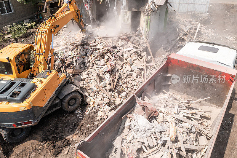 挖掘机将建筑垃圾装入卡车。拆除危房