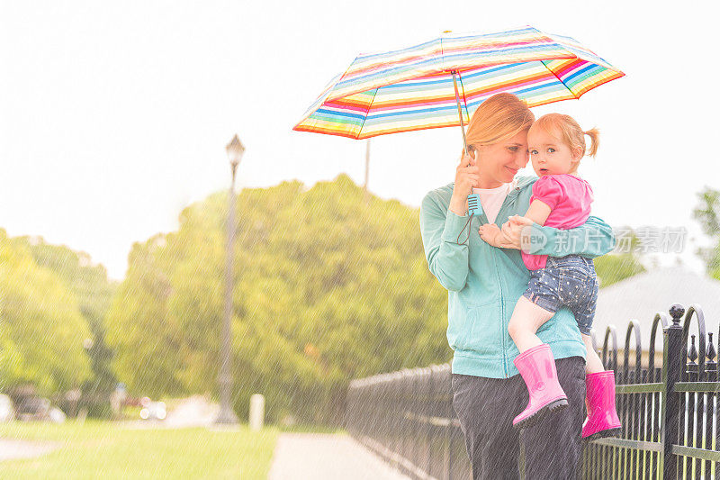 快乐的母女在雨中的雨伞下