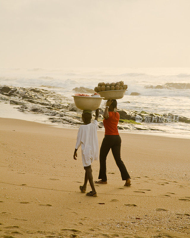 加纳:黎明时分，妇女们在海滩上扛着货物去市场