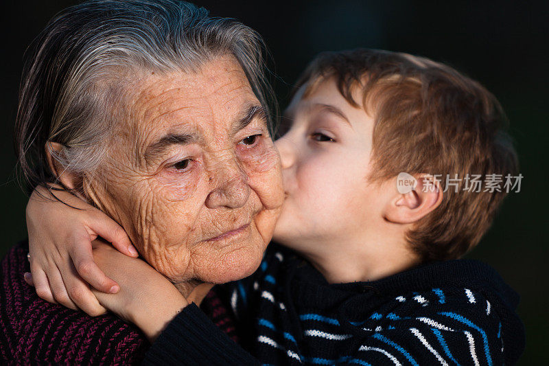 孙子在黑色背景下亲吻他的曾祖母
