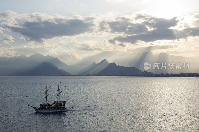 双桅船航行在平静的大海，山脉