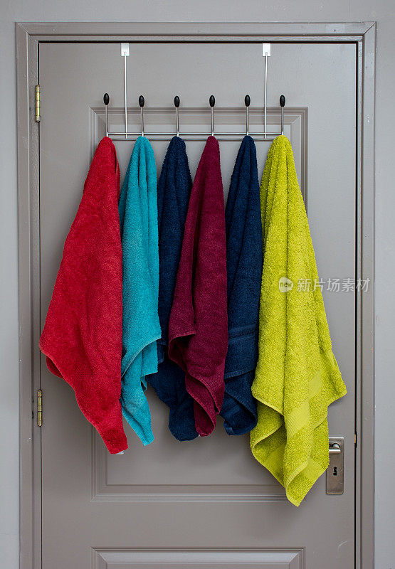 门里面的衣架上放着多种颜色的毛巾